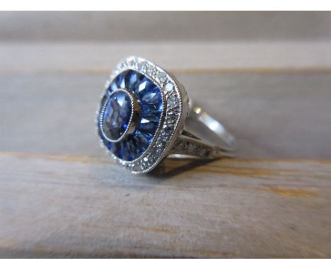 Platinum ring set central sapphire bordered by calibre cut sapphires and diamonds 