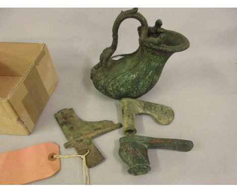 Two antique bronze patinated axe heads, part of a bronze oriental sword blade and an antique bronze (possibly Roman) jug with