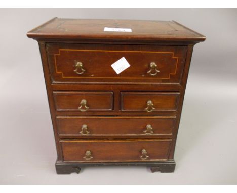 19th Century miniature mahogany and inlaid chest with a fitted secretaire drawer above two short and two long drawers on brac