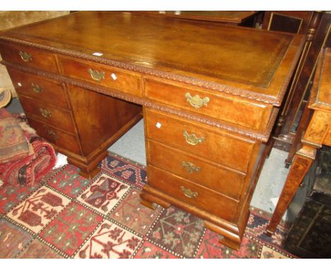 Early 20th Century burr walnut twin pedestal desk in early 18th Century style, having brown leather inset top above a carved 