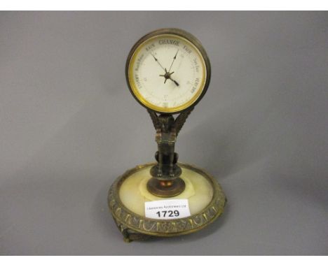 19th Century gilt brass and onyx desk barometer, the enamel dial within a drum form case supported by Egyptianesque winged be