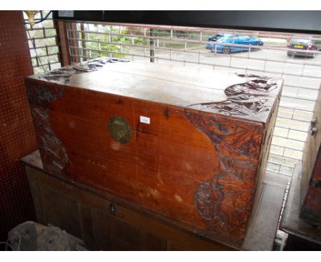 Oriental carved camphor wood trunk decorated in deep relief with stylised flowers, the hinged lid above a brass hasp and stap