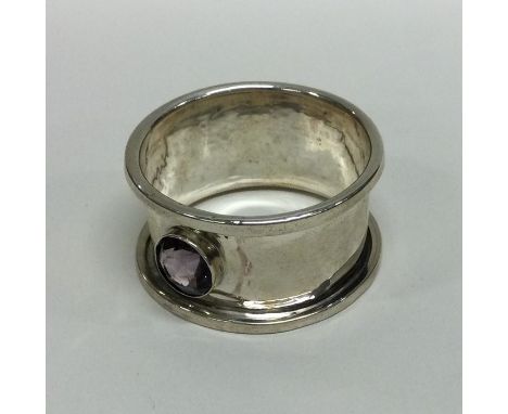 An Arts &amp; Crafts silver napkin ring mounted with an amethyst. Approx. 14 grams. Est. £10 - £20.