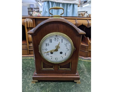 A late 19th/early 20th century mahogany mantel clock having an arched top, white enamel dial and 8-day movement striking on a