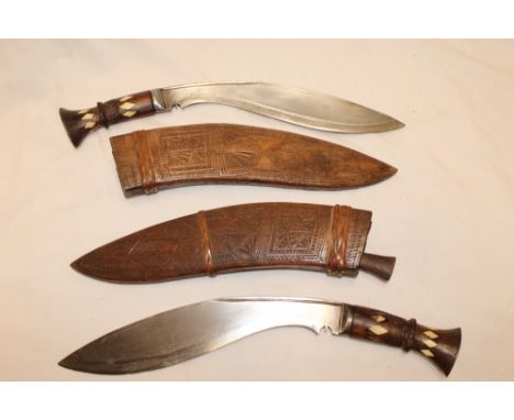 A pair of Gurkha kukri with curved single edged blades, bone inlaid hilts and carved wood scabbards