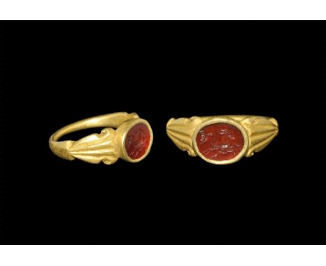 3rd century AD. 
A gold D-section hoop with flared shoulders and scrolled edges, discoid plaque with inset carnelian cloison 