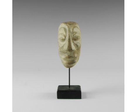 Pliocene, 5.2-2.5 million years BP. A Javanese mastodon fossil bone carving, a face with lentoid eyes and parted lips; mounte
