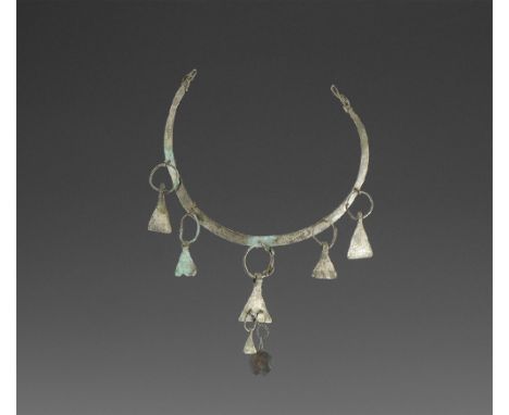 9th-11th century AD. 
A silver torc with twisted ends forming loops, body of the torc decorated with punched dot triangles; a