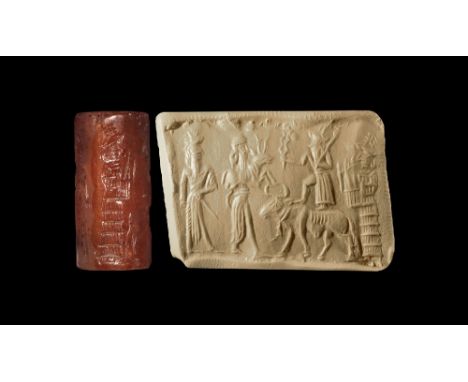 10th-5th century BC.
A carved carnelian cylinder seal with frieze of two robed figures facing a bull with attendant in a flou