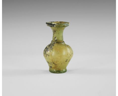 3rd-4th century AD. 
A piriform glass flask with dimple base, ribbed body, tubular neck with restriction to the lower end, fl