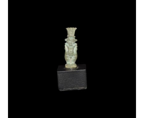Late Period, 664-332 BC. 
A pale blue glazed composition amulet of Bes in feathered headdress, with dorsal pillar pierced in 