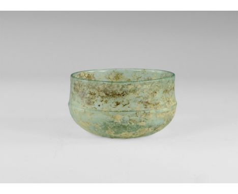 3rd-4th century AD.
A pale blue-green glass bowl with dimple base and carinated profile with raised circumferential rib. 95 g