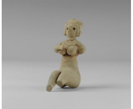 3rd millennium BC. 
A ceramic figure of a nude female, seated with legs projecting forward and slightly bent at the knees; ar