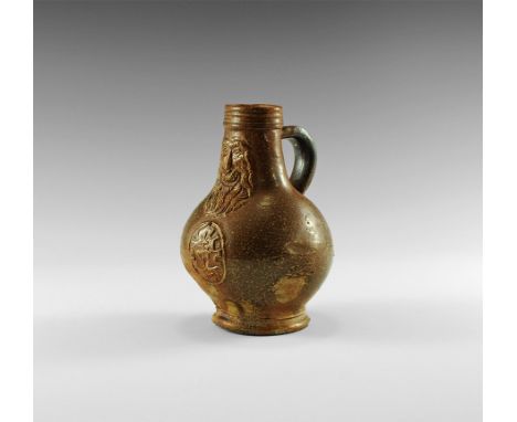 1600 AD. 
A stoneware Bartmannkrug jug with bearded face motif below the rounded rim, C-section handle to the neck, heraldic 