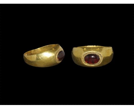 4th-5th century AD. A carinated gold hoop with expanding shoulders, domed plaque with cabochon garnet insert. 7.52 grams, 23m