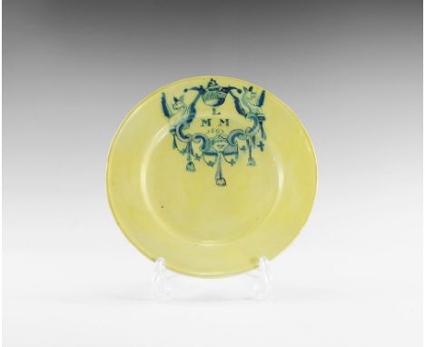 Dated 1687 AD. 
A shallow ceramic plate with the design of a coronet supported by a pair of winged demi-beasts (griffins?) wi