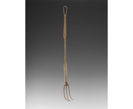 1st-3rd century AD. A hand-forged iron fork with three curved tines, waisted shaft with twist to the centre, loop to the uppe
