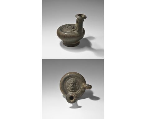 4th century BC. 
A large blackware ceramic guttos with broad pedestal base, discoid body, loop handle and waisted spout, ribs