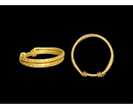 9th-11th century AD.
A flat-section gold hoop formed from a single coiled rod with pellets to the outer face, narrow ends twi