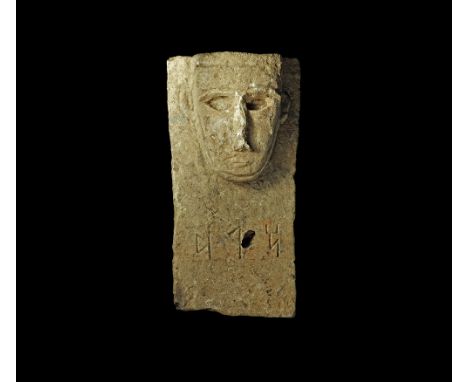 2nd century BC-2nd century AD. 
The top of a rectangular alabaster stele with stylised human face carved in the half-round wi