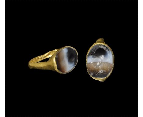 3rd-2nd century BC. 
A hollow gold D-section hoop and drum-shaped bezel with inset banded agate plaque, intaglio profile bust