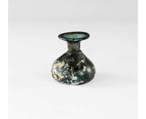 3rd-4th century AD.
A squat iridescent glass flask with dimple base,constricted neck, flared and turned rim. 16 grams, 50mm (