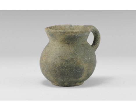 2nd millennium BC.
A ceramic cup with flaring rim and globular body with attached handle. 150 grams, 80mm (3 1/4"). [No Reser
