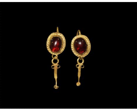 1st-2nd century AD. A matched pair of gold earrings, each a discoid plaque with ribbed border to the cell, cabochon garnet in