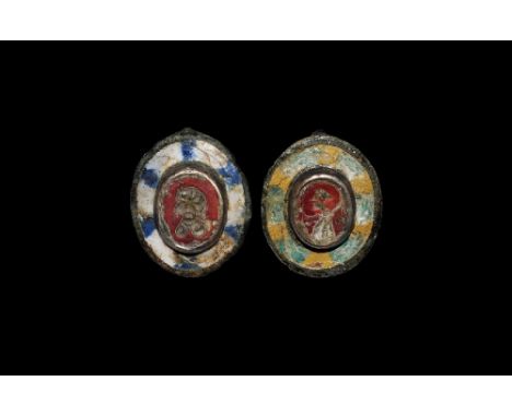 2nd century AD.
A pair of tinned-bronze plate brooches comprising: ovoid plaque with radiating green and yellow enamel bars, 