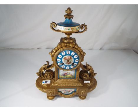 A decorative spelter cased French mantel clock with inset porcelain panels showing figural scenes against a blue background, 