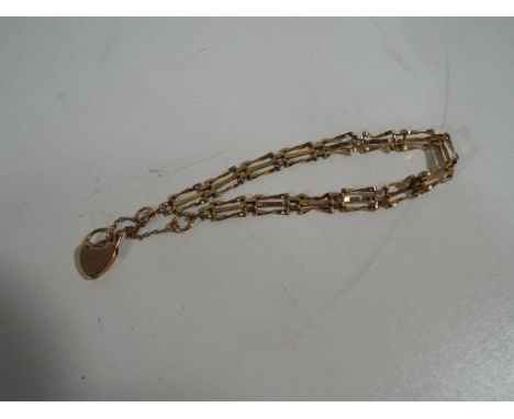 A 9 carat gold gate bracelet with safety chain and padlock, approximate weight 3.93 grams. Estimate £30 - £50