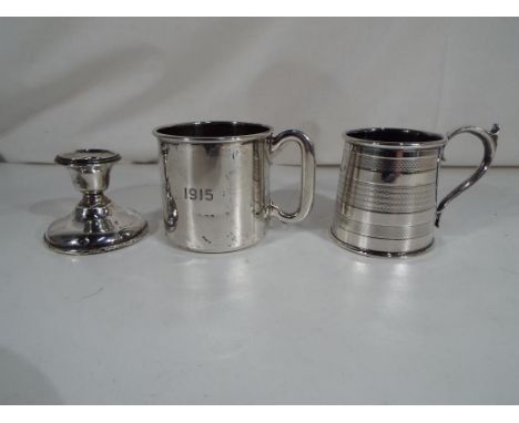 A silver candlestick Birmingham Assay, date mark rubbed, a christening cup stamped 'Sterling' engraved 1915 and a further sil