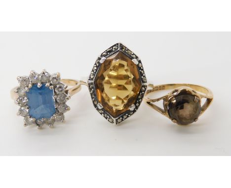 A 9ct gold blue and clear gem set ring size N1/2, a 9ct smoky quartz ring size L1/2, and a yellow and white metal brown gem a