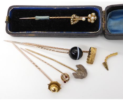 A collection of stick pins to include two yellow metal pearl set pins, the yellow metal mount from a tiger's claw pin, a 9ct 