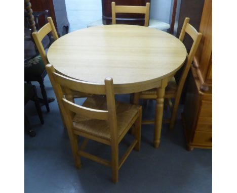 A LIGHT OAK EFFECT CIRCULAR KITCHEN DINING TABLE, EXTENDING WITH A FOLDING LEAF BELOW AND A SET OF FOUR BEECHWOOD DINING CHAI