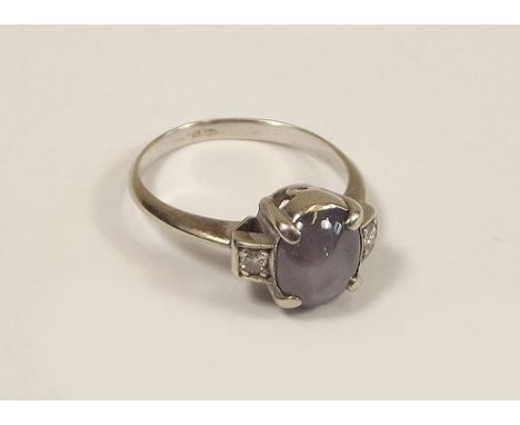 STAR SAPPHIRE.
A dress ring set a star sapphire between diamond set shoulders, in white metal. Stone approx. 8 x 7mm. Size M/