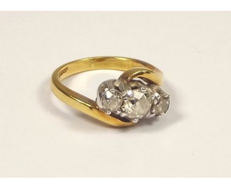 DIAMOND RING.
An 18ct. gold, three stone crossover ring, the largest stone of approx. 0.60ct. spread. Flanking stones each ap