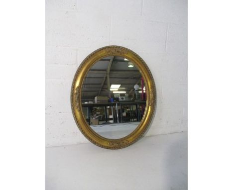 A gilt framed oval mirror.