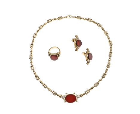 centred with an oval-shaped carnelian with a collet set circular-cut diamond set to each shoulder, in 18ct gold, on a fancy l