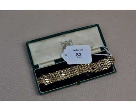 A yellow metal, partially engraved gate link bracelet