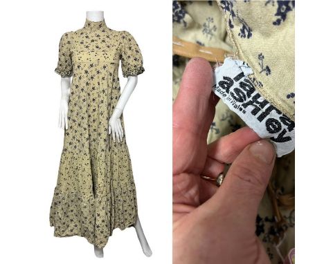 An early 1970s Laura Ashley prairie dress in off white with a blue floral print. Empire line bust. Replacement zipper has bee