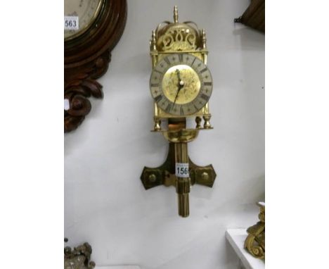 A large brass lantern clock on wall bracket