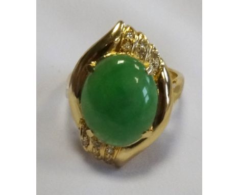 JADE AND DIAMOND DRESS RINGthe central oval cabochon jade within a diamond set shaped surround, on fourteen carat gold shank,