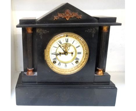 AMERICAN BLACK SLATE MANTLE CLOCKlate 19th century, the shaped top above a circular dial with Roman numerals and a visible es