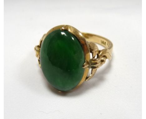 JADE DRESS RINGthe oval cabochon jade on fourteen carat gold shank with decorative pierced and scroll shoulders, ring size J-