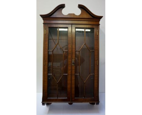 MAHOGANY WALL MOUNTING CABINETwith swan neck pediment, above a pair of glazed astragal doors, with glazed shelf interior, 107