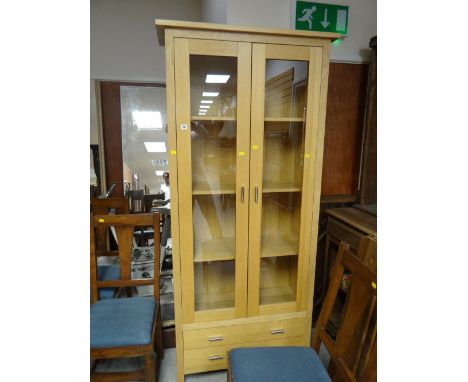 A modern light oak two-door display cabinet with a two-drawer base