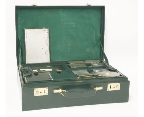A green leather dressing case,the fitted interior with French silver-gilt mounted glass jars and brushes, the top fitted tray