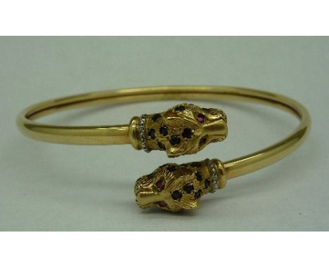 A 9ct gold bangle with stone set leopard heads, weight 11.6g