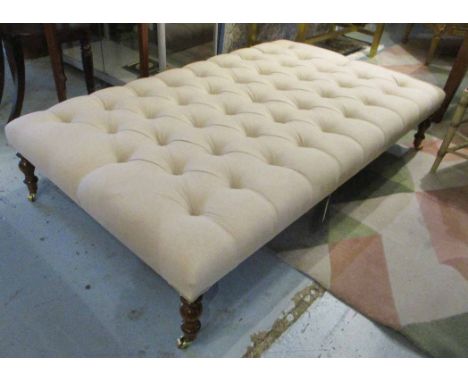 HEARTH STOOL, with buttoned beige upholstery on short turned supports with castors, 154cm W x 34cm H x 93cm D.
